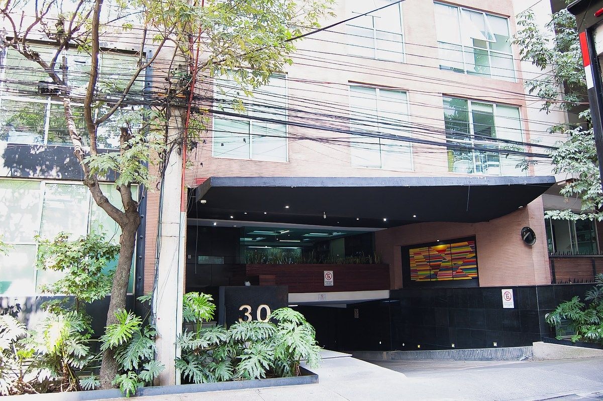Fachada del condominio, se aprecia la entrada peatonal del lado izquierdo y la rampa para el acceso vehicular del lado derecho de la imagen